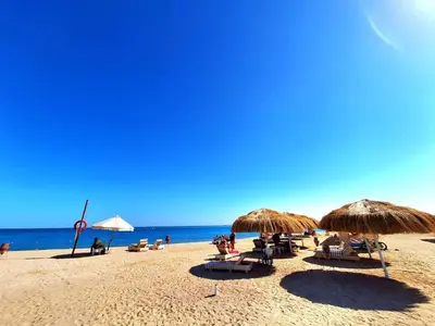 a beach with chairs and umbrellas and the ocean at Princess Resort in Hurghada