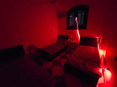 a red room with two beds and a window at Golden home in Aswan