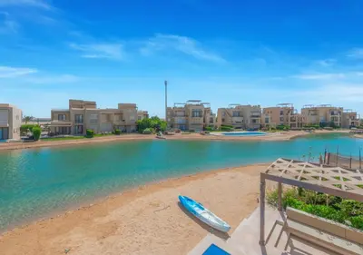 a boat sitting on the beach in front of buildings at Breezy Lagoonfront Escape 3BR with Private Pool I Tawila El Gouna in Hurghada