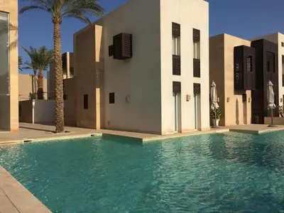 a swimming pool in front of a building with palm trees at elgouna scarab es first floor in El Gouna