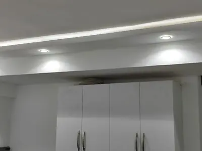 a kitchen with white cabinets and lights on the ceiling at Cozy Modern Apartament in Hurghada
