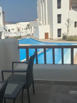 a table and a chair on a balcony with a swimming pool at Tranquil 3-Bedroom Holiday Home in Makadi Heights, Hurghada - Private Rooftop Pool, Lagoon and More in Hurghada
