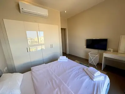 a bedroom with a white bed and a tv at Panoramic 2BR Apt-Free Pool And Lagoon Access At ElGouna in Hurghada