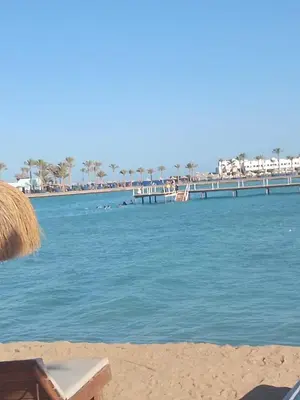 a beach with chairs and a dock in the water at Tiba Golden Resort Hurghada in Hurghada