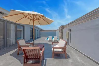 a patio with chairs and a table and an umbrella at Luxury 2 Bedrooms in Bali - Elgouna with pool in Hurghada