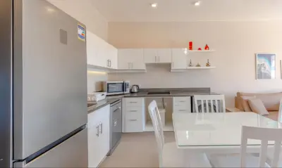 a kitchen with white cabinets and a table and a dining room at Luxury Stays in Cyan El Gouna in Hurghada