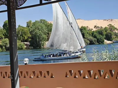 a boat with a large white sail on the water at Villa Swenet in Aswan