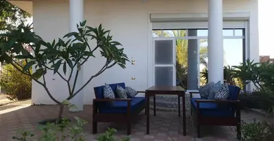 a patio with blue chairs and a table and a tree at Jahmed Country Villa Luxor West Bank in Al Aqālitah