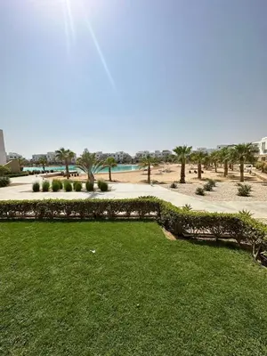 a park with green grass and a beach with palm trees at Ground Modern Apartment in Hurghada