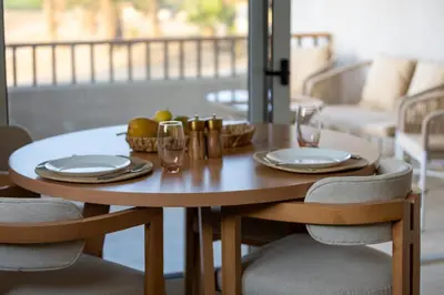 a wooden table with plates and glasses on it at Breeze, Golf & Sea, 2 BR Luxury Apt with Terrace, Somabay in Hurghada