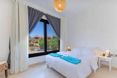 a bedroom with a white bed and a large window at Modern 2 bedroom apartment in El Gouna with pool in Hurghada