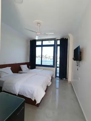 two beds in a room with a large window at New El Amin Guesthouse in Aswan