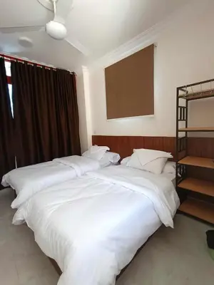 two beds in a room with white sheets at New El Amin Guesthouse in Aswan