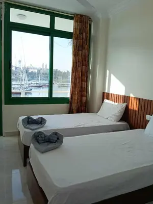 two beds in a room with a window at New El Amin Guesthouse in Aswan