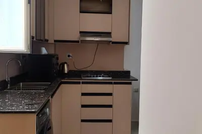 a kitchen with brown cabinets and a stove top oven at Hurghada HUB Resort in Hurghada