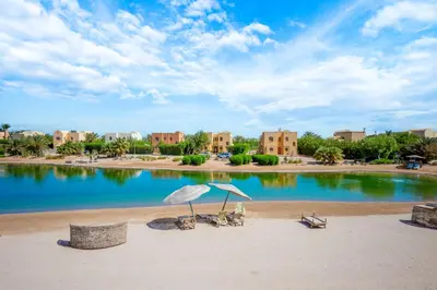 a beach with two chairs and an umbrella at Luxury Stays in Nubia El Gouna in Hurghada