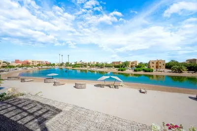 a pool with chairs and umbrellas on a beach at Luxury Stays in Nubia El Gouna in Hurghada