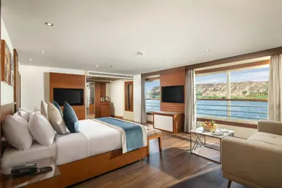 a bedroom with a large bed and a living room at 4 nighhts luxury Nile cruise from Luxor to Aswan in Qena