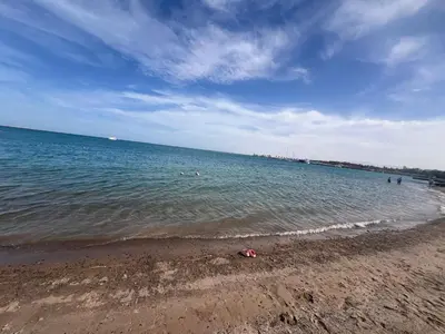 a beach with people swimming in the water at Luxury Suite Princess Resort Two bedroom apartment Hurghada سويت فاخر البرنسيسه غرفتين in Hurghada