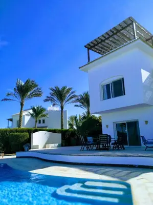 a white house with palm trees and a swimming pool at Coral Blue 'An expansive spacious 4 bedroom villa in El Gouna' in Hurghada