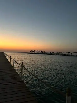 a boardwalk leading into the ocean at sunset at منتجع سكانديك الغردقة in Hurghada
