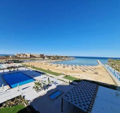 a beach with a pool and chairs and the ocean at منتجع سكانديك الغردقة in Hurghada