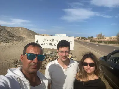 a group of three people standing in front of a sign at king tut apartment in Luxor