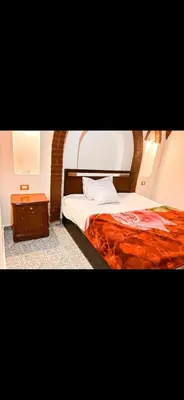 a bedroom with a bed and a night stand at Paradise Apartments in Al Aqālitah