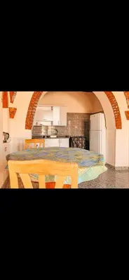 a kitchen with a table and a dining room at Paradise Apartments in Al Aqālitah
