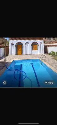 a picture of a blue swimming pool in front of a house at Paradise Apartments in Al Aqālitah