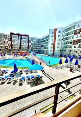 a large swimming pool with blue umbrellas and chairs at Hurghada Studio Tiba Golden Resort in Hurghada