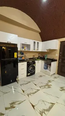 a kitchen with white cabinets and a marble floor at Sun Roof in Hurghada