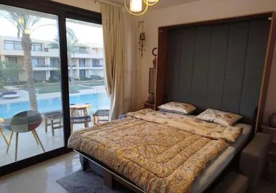 a bedroom with a large bed and a balcony with a pool at Studio at G Cribs B21-F10 El Gouna in Hurghada