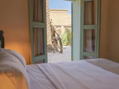 a bedroom with an open window with a bed and a view at Habu Hotel in Al Aqālitah