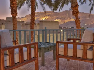 a balcony with palm trees and a table and chairs at Habu Hotel in Al Aqālitah