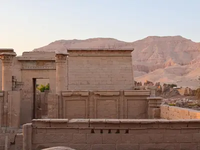an ancient building with a mountain in the background at Habu Hotel in Al Aqālitah