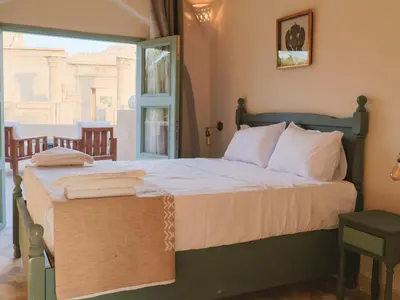 a bedroom with a bed with white sheets and a window at Habu Hotel in Al Aqālitah