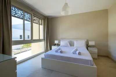 a bedroom with a white bed and a large window at Mangroovy 1BR + Sofa bed • Pool & Beach Access in Hurghada