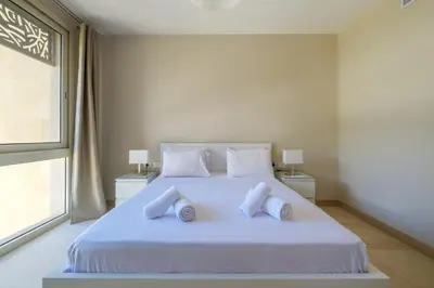 a bedroom with a white bed with two pillows at Mangroovy 1BR + Sofa bed • Pool & Beach Access in Hurghada
