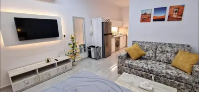 a living room with a couch and a flat screen tv at Hurgada New studio in Avenue on Mamsha -private beach&pool in Hurghada