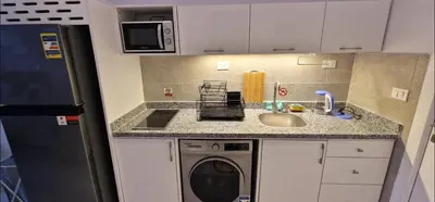 a small kitchen with a washing machine and a sink at Hurgada New studio in Avenue on Mamsha -private beach&pool in Hurghada