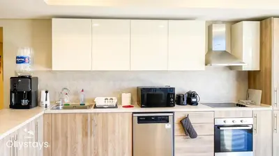 a kitchen with white cabinets and a microwave at Ollystays Mangrovy Seaview Penthouse 3BR Beach & Pool access in Hurghada
