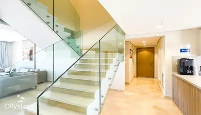 a staircase in a house with glass railing at Ollystays Mangrovy Seaview Penthouse 3BR Beach & Pool access in Hurghada
