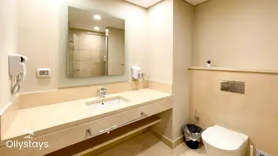 a bathroom with a sink and a mirror and a toilet at Ollystays Mangrovy Seaview Penthouse 3BR Beach & Pool access in Hurghada