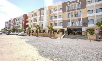 a large building with palm trees in front of it at Aqua Infinity in Hurghada