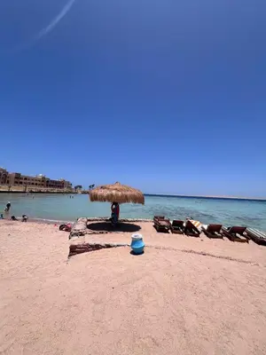 a group of chairs and an umbrella on a beach at Hurghada Tiba Golden Resort Apartment Strand Pool 22 in Hurghada