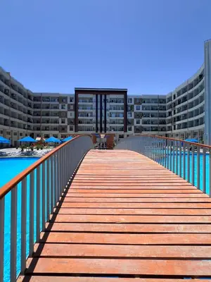 a wooden walkway leading to a large apartment building at Hurghada Tiba Golden Resort Apartment Strand Pool 22 in Hurghada
