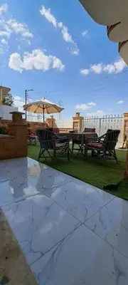a patio with benches and a table and an umbrella at Egypt Soul hotel retreat in Luxor