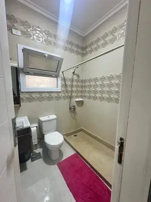 a bathroom with a toilet and a pink rug at Bostan in Hurghada