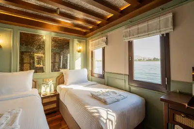 two beds in a room with a window at HMC Zahra Dahabyia in Luxor
